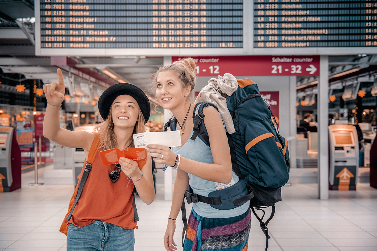 Zwei Studierende am Flughafen mit Gepäck