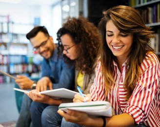 Three students are sitting next to each other in the library.