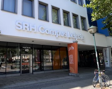 SRH Campus Leipzig Header neu SRH Campus Leipzig with an entrance area and signs. Bicycles are parked in front of the building, which showcases modern architecture.