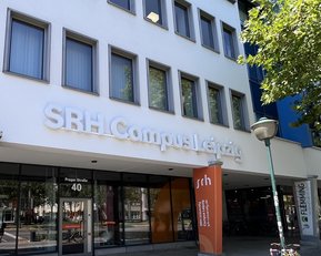 SRH Campus Leipzig mit Eingangsbereich und Schildern. Fahrräder stehen vor dem Gebäude, das moderne Architektur zeigt.