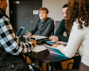 Studierende unterhalten sich im Klassenzimmer.