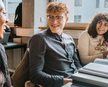 Drei Studienkollegen sind im Gespräch im Klassenraum der SRH University.