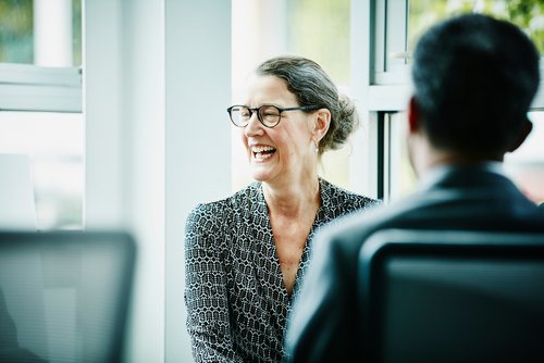 Frau mit Brille lacht während eines Gesprächs