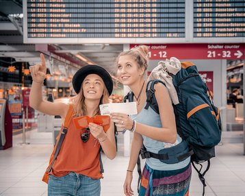 Zwei Studierende am Flughafen mit Gepäck