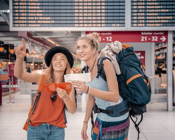 Zwei Studierende am Flughafen mit Gepäck