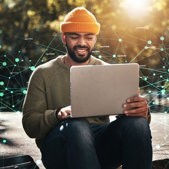 Ein Mann mit einem orangefarbenen Hut sitzt im Freien und arbeitet an einem Laptop. Um ihn herum sind digitale Netzwerkverbindungen dargestellt. Die Sonne scheint, und er lächelt, während er auf den Bildschirm schaut.