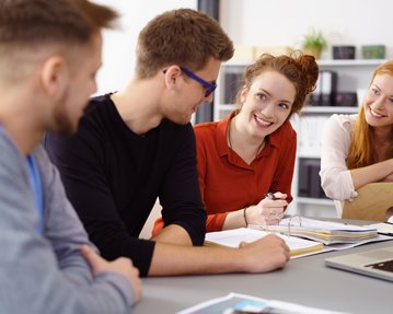 Studierende lächelnd sitzen gemeinsam in einem Raum