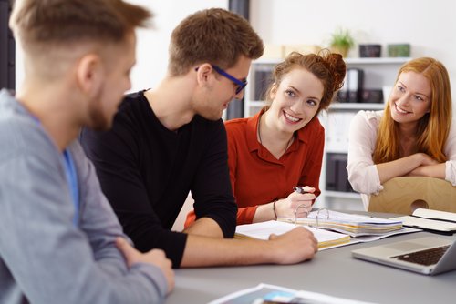 Studierende lächelnd sitzen gemeinsam in einem Raum