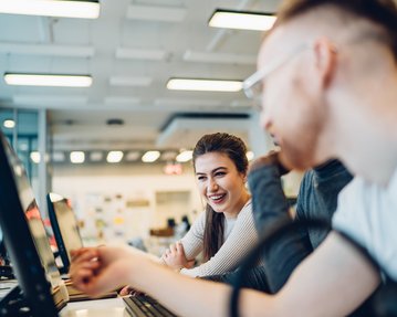 Studierende sitzen gemeinsam vor einem PC