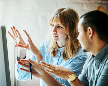 Mann und Frau diskutieren vor Bildschirm