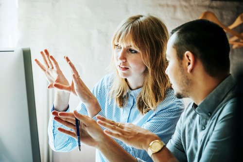 Mann und Frau diskutieren vor Bildschirm