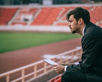 Mann sitzt auf Tribüne im Fußballstadion