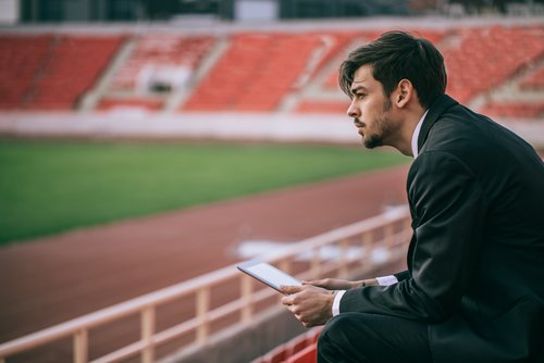 Mann sitzt auf Tribüne im Fußballstadion