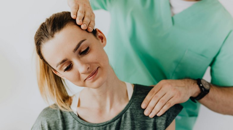 Kategorie Therapie studieren Studium SRH University A woman is receiving a neck massage from a male therapist. The therapist has his hand on her head while she looks relaxed. Both are wearing comfortable clothing.