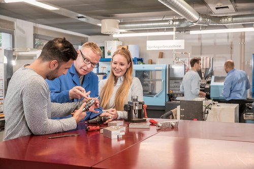 Studierende im Bereich Maschinenbau arbeiten gemeinsam mit Professor an CNC- und Spritzgussmaschinen