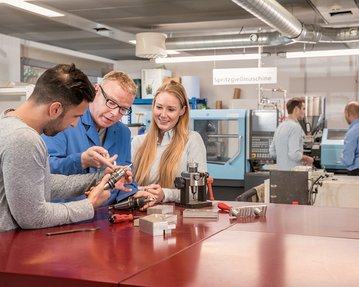 Studierende im Bereich Maschinenbau arbeiten gemeinsam mit Professor an CNC- und Spritzgussmaschinen