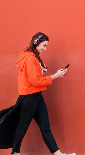 Studentin mit Handy in der Hand läuft an einer roten Wand vorbei