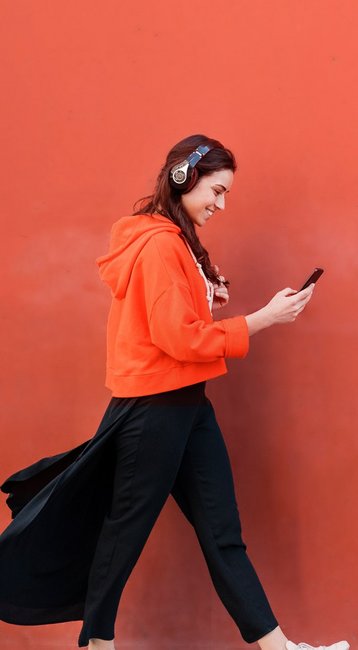 Studentin mit Handy in der Hand läuft an einer roten Wand vorbei