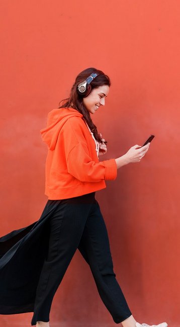 Studentin mit Handy in der Hand läuft an einer roten Wand vorbei