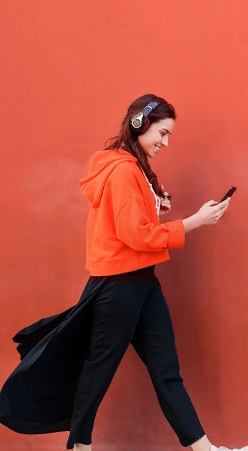 Studentin mit Handy in der Hand läuft an einer roten Wand vorbei