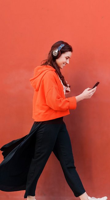 Studentin mit Handy in der Hand läuft an einer roten Wand vorbei