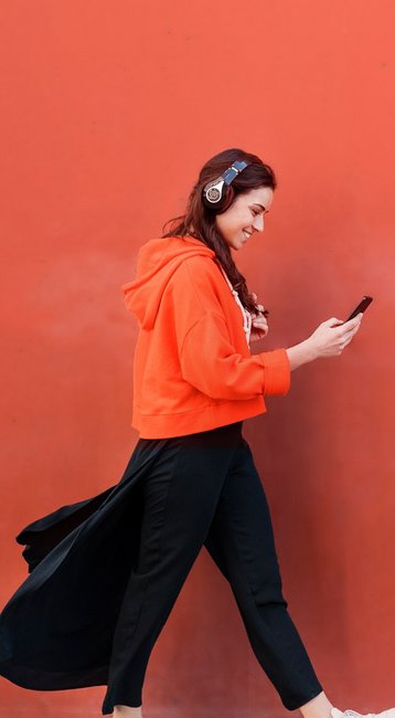 Studentin mit Handy in der Hand läuft an einer roten Wand vorbei