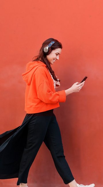 Studentin mit Handy in der Hand läuft an einer roten Wand vorbei