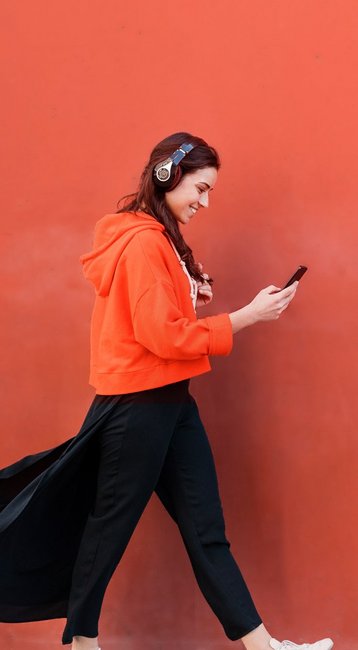 Studentin mit Handy in der Hand läuft an einer roten Wand vorbei