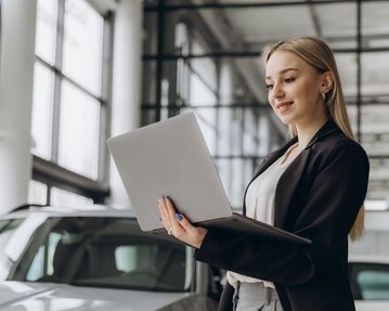 Frau im Autohaus mit Laptop in den Händen